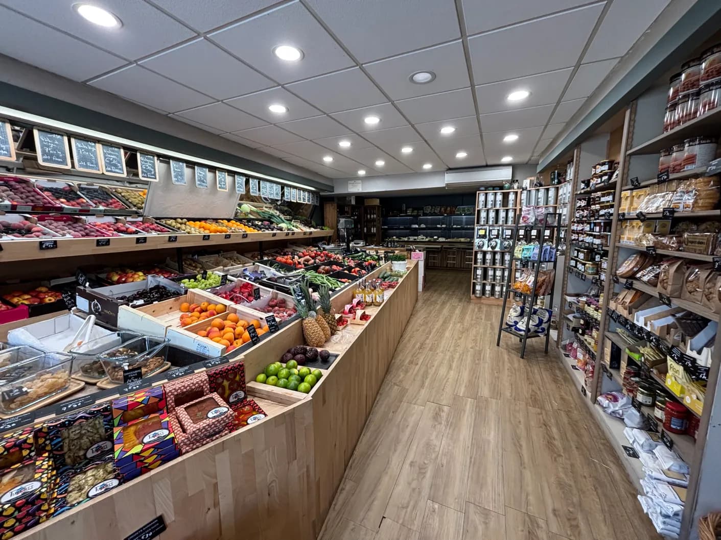 L'intérieur de la boutique Au Jardin Fromager à Melesse : étals de fruits et légumes et rayons d'épicerie fine